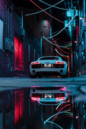 White Audi R8 parked in a dark alley with neon reflections