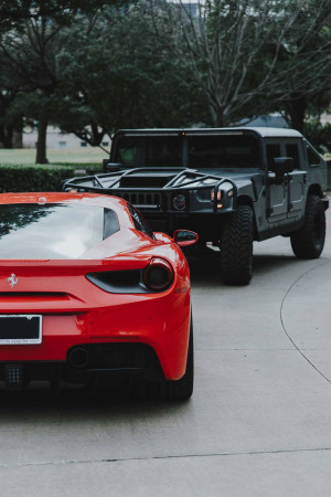 Red Ferrari and Black Hummer H2 parked on a driveway