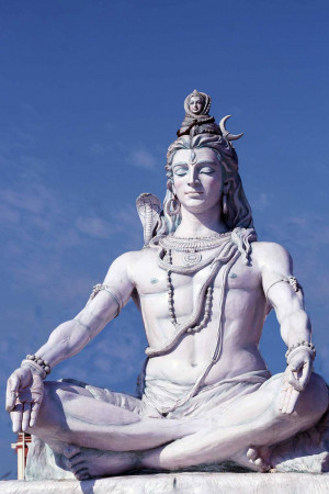 A large white statue of Lord Shiva in a meditative pose.
