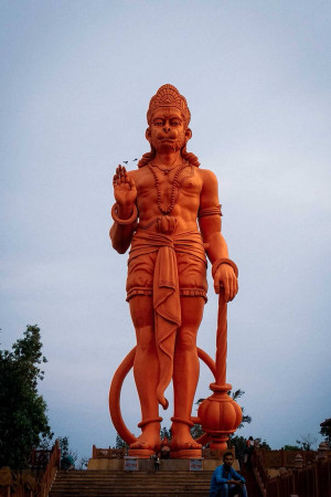 Large orange Hanuman statue against a blue sky