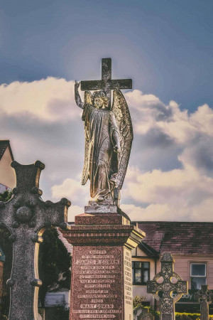 Bronze angel statue with wings raised in a graveyard