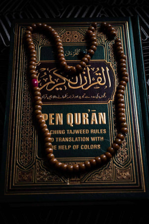 A Quran with a tasbih (prayer beads) draped over it.