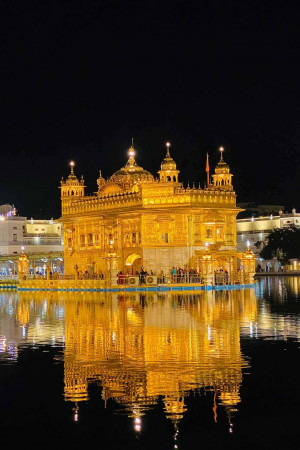 The Golden Temple, Harmandir Sahib, illuminated at night with its reflection in the surrounding water.