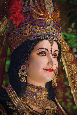 Close-up of a beautifully decorated Durga idol with intricate jewelry and vibrant colors.