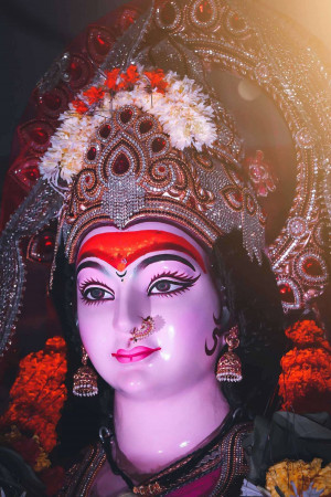 Close-up of a beautifully decorated Durga idol with a floral crown and intricate jewelry.