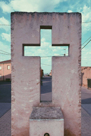 A tall concrete cross-shaped monument against a blue sky with clouds.