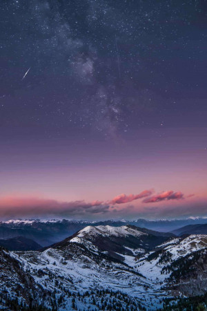 Snow-capped mountains under a vibrant starry night sky with the Milky Way visible