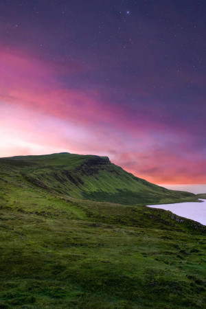 A stunning night view of a mountain range in Iceland with a vibrant aurora borealis.