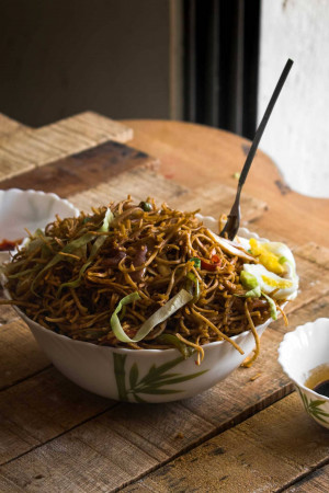 A close-up of a bowl of Hakka noodles with vegetables and egg.