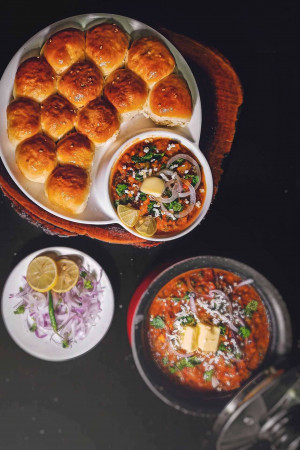 Overhead shot of Pav Bhaji, a popular Indian street food, served with lemon wedges and onions.