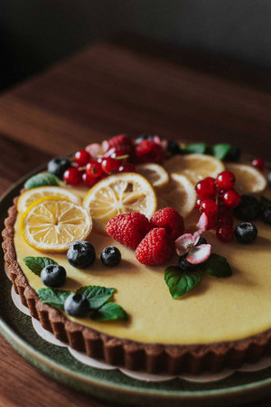 Close-up of a lemon tart decorated with fresh berries and lemon slices