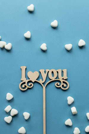 Wooden 'I Love You' sign surrounded by white marshmallows on a blue background