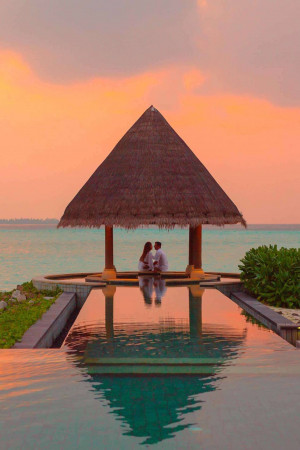 Couple embracing in a gazebo over the water at sunset