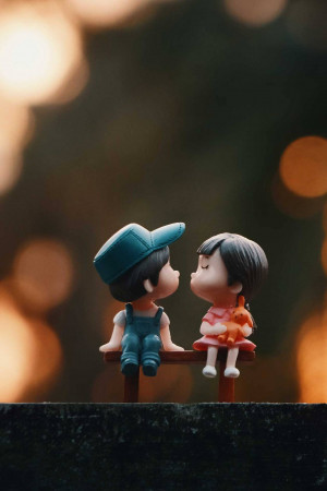Two small figurines of a boy and girl sitting close together on a bench.