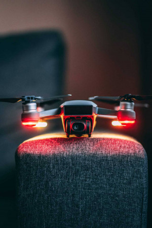 Close-up of a drone with illuminated lights resting on a textured surface.