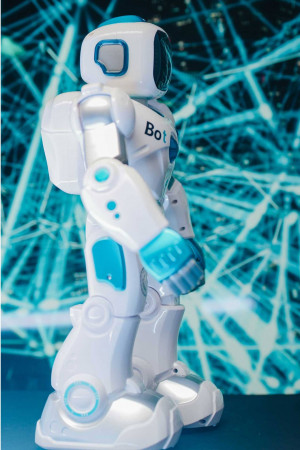 White and blue humanoid robot standing against a blurred blue background.