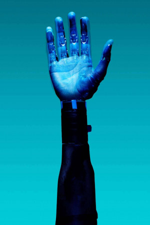 Close-up of a blue robotic hand raised against a teal background