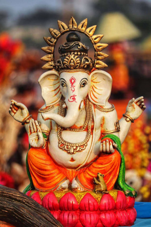 Close-up of a beautifully decorated Lord Ganesha idol with a blurred festive background.
