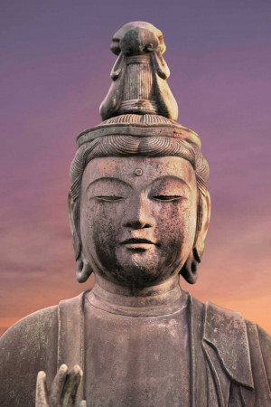 Close-up of a weathered stone Buddha head against a vibrant sunset sky