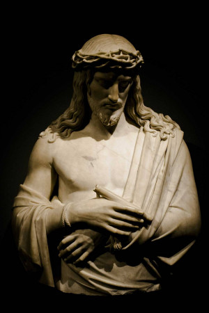 Marble statue of Jesus Christ wearing a crown of thorns, looking downwards with hands clasped.