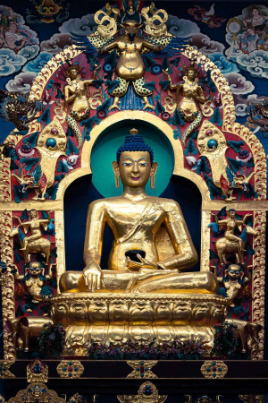 Close-up of a golden Buddha statue with intricate details and colorful background.