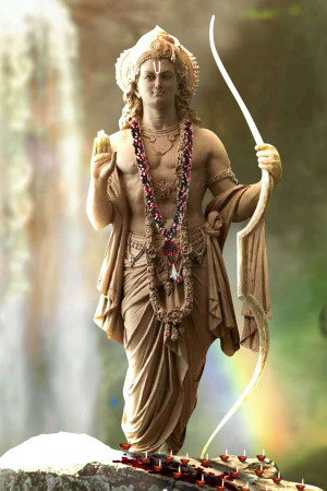 Statue of Lord Rama holding a bow and arrow, adorned with flowers and jewelry.