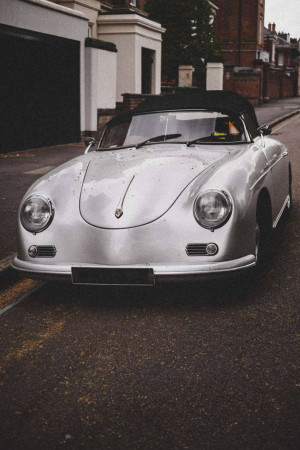 Front view of a silver vintage Porsche 356 Speedster parked on a residential street.