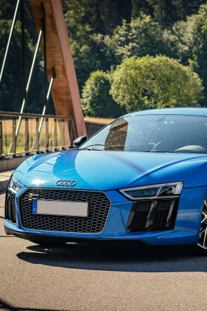 Front view of a bright blue Audi R8 sports car on a bridge