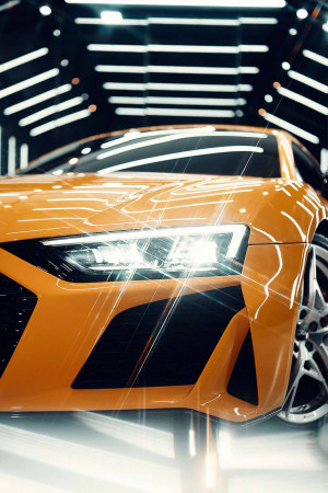Close-up of a vibrant orange sports car parked in a modern, illuminated tunnel.