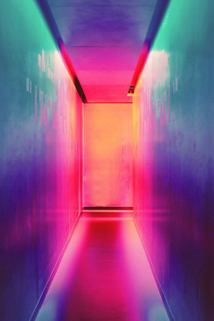 A long corridor illuminated with vibrant neon lights in shades of pink, purple, and orange.