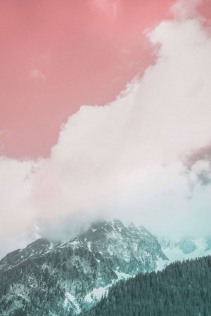 Snow-capped mountains partially obscured by clouds under a pink and teal sky