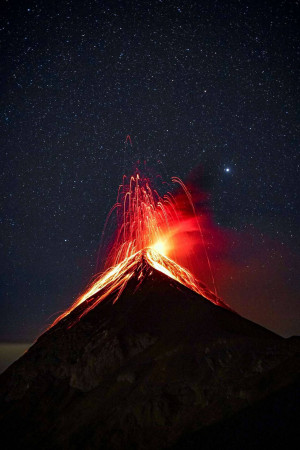 A majestic volcano erupting at night with a starry sky backdrop.