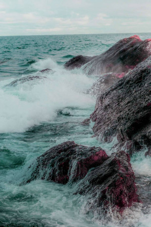 Waves crashing against dark rocky coastline