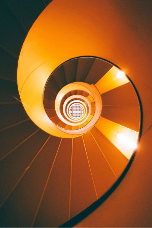 Looking up a spiral staircase with warm lighting