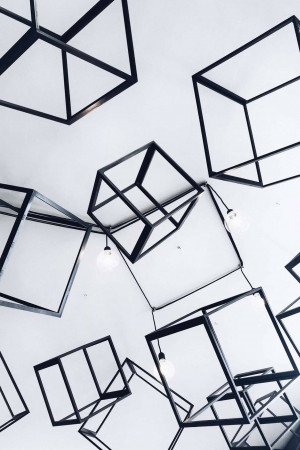 Abstract art installation featuring black geometric shapes and hanging lights.