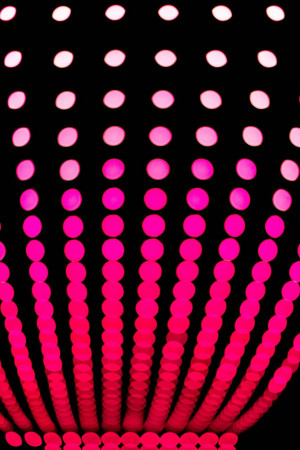 Close-up of pink and red neon lights arranged in a circular pattern against a black background.