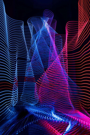 Abstract image of swirling neon light trails in blue, pink, and red against a black background.