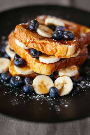 Stack of French toast topped with blueberries and banana slices