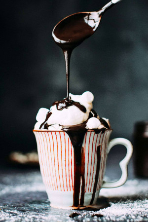 Close-up of hot chocolate being poured into a mug with marshmallows