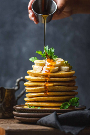 A stack of pancakes drizzled with golden syrup and garnished with mint and banana slices.