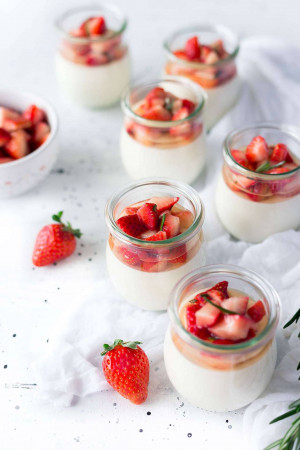 Close-up of strawberry yogurt parfaits in small glass jars with fresh strawberries