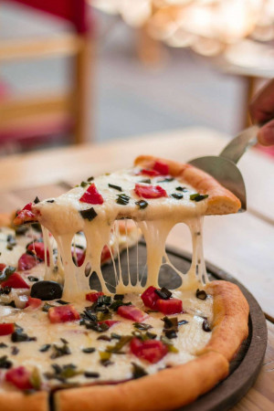 A close-up shot of a pizza slice being lifted, with melted cheese stretching.