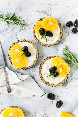 Overhead shot of three small tarts with citrus and blackberries