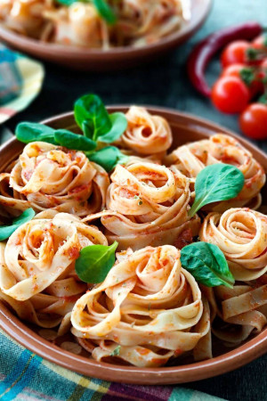 Close-up of pasta arranged like roses in a tomato sauce