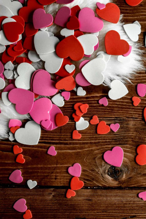 Scattered hearts on a white fur background with a wooden surface