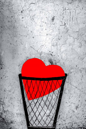 A red heart in a black trash can against a textured gray background.
