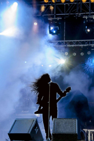 Silhouette of a guitarist performing on stage with smoke and lights