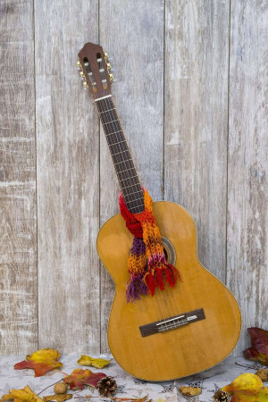 Acoustic guitar with a colorful scarf and autumn leaves