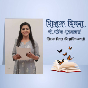 A woman holding a book with a Teachers Day greeting in Hindi.