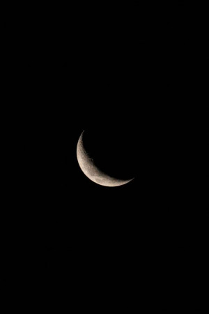 A delicate waxing crescent moon against a black sky.